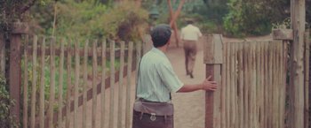 Movie still from “Burning Patience” (2022), directed by Rodrigo Sepúlveda – A man standing next to a wooden fence; Wide shot, Over the shoulder angle
