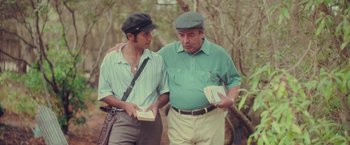 Movie still from “Burning Patience” (2022), directed by Rodrigo Sepúlveda – Two men standing next to each other in the woods; Medium shot, Low angle