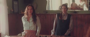 Movie still from “Burning Patience” (2022), directed by Rodrigo Sepúlveda – Two women standing next to each other in front of a window; Medium shot, Over the shoulder angle