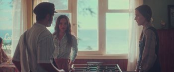 Movie still from “Burning Patience” (2022), directed by Rodrigo Sepúlveda – Two people standing in front of a table with a table football game on top of it; Medium shot, Over the shoulder angle