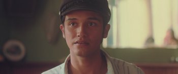 Movie still from “Burning Patience” (2022), directed by Rodrigo Sepúlveda – A person wearing a hat; Close Up shot, Over the shoulder angle