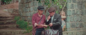 Movie still from “Burning Patience” (2022), directed by Rodrigo Sepúlveda – A man and a man in a suit and a hat; Medium shot, High angle