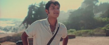 Movie still from “Burning Patience” (2022), directed by Rodrigo Sepúlveda – A young man wearing a white shirt and a black bag; Close Up shot, Low angle