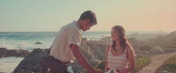 Movie still from “Burning Patience” (2022), directed by Rodrigo Sepúlveda – A man and a woman standing next to each other on the beach; Medium shot, Low angle