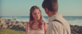 Movie still from “Burning Patience” (2022), directed by Rodrigo Sepúlveda – A man and a woman standing next to each other on the beach; Close Up shot, Over the shoulder angle