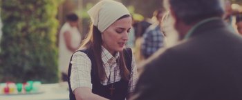 Movie still from “Burning Patience” (2022), directed by Rodrigo Sepúlveda – A woman wearing a head scarf and a cross necklace; Close Up shot, Over the shoulder angle
