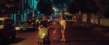 Movie still from “Burning Patience” (2022), directed by Rodrigo Sepúlveda – A man and a woman standing on the side of the street; Wide shot, High angle