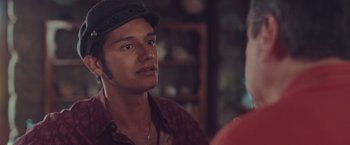 Movie still from “Burning Patience” (2022), directed by Rodrigo Sepúlveda – A man wearing a hat looking at a woman; Close Up shot, Over the shoulder angle