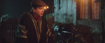 Movie still from “Burning Patience” (2022), directed by Rodrigo Sepúlveda – A man wearing a hat and a jacket; Medium shot, Over the shoulder angle
