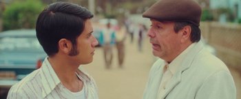 Movie still from “Burning Patience” (2022), directed by Rodrigo Sepúlveda – A man and a boy talking to each other outside; Close Up shot, Over the shoulder angle