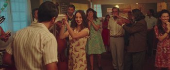 Movie still from “Burning Patience” (2022), directed by Rodrigo Sepúlveda – A group of people standing in a room; Medium shot, Over the shoulder angle