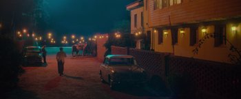 Movie still from “Burning Patience” (2022), directed by Rodrigo Sepúlveda – A car parked on the side of the road at night; Extreme Wide shot, High angle