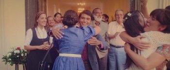 Movie still from “Burning Patience” (2022), directed by Rodrigo Sepúlveda – A man and a woman hugging in front of an audience; Medium shot, Over the shoulder angle