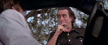 Movie still from “Cape Fear” (1991), directed by Martin Scorsese – A man in a black shirt is smoking a cigarette in the back of a car; Close Up shot, Low angle