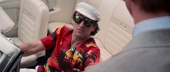 Movie still from “Cape Fear” (1991), directed by Martin Scorsese – A man wearing a hawaiian shirt and a hat sitting in a car; Medium shot, Low angle