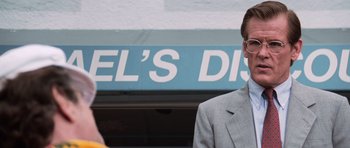 Movie still from “Cape Fear” (1991), directed by Martin Scorsese – A man in a suit and tie standing in front of a store; Close Up shot, Low angle