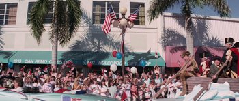A crowd of people standing in front of a building with american flags