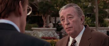Movie still from “Cape Fear” (1991), directed by Martin Scorsese – An older man wearing a suit and tie in front of a fountain; Close Up shot, Over the shoulder angle