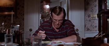 Movie still from “Cape Fear” (1991), directed by Martin Scorsese – A man sitting at a dinner table with a fork in his hand; Medium shot, Over the shoulder angle