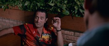 Movie still from “Cape Fear” (1991), directed by Martin Scorsese – A man sitting at a table holding a cigar; Medium shot, Low angle