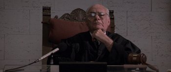 Movie still from “Cape Fear” (1991), directed by Martin Scorsese – An older man in a judge's robe sitting at a podium; Close Up shot, Low angle