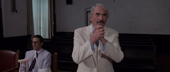 Movie still from “Cape Fear” (1991), directed by Martin Scorsese – An older man in a white suit is praying; Medium shot, Low angle