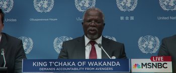 Movie still from “Captain America: Civil War” (2016), directed by Anthony Russo – A man in a suit and red neck tie is giving a speech; Close Up shot, Low angle