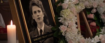 Movie still from “Captain America: Civil War” (2016), directed by Anthony Russo – A portrait of a woman next to a flower arrangement; Close Up shot, Over the shoulder angle