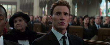 Movie still from “Captain America: Civil War” (2016), directed by Anthony Russo – A man in a suit and tie in front of a group of people; Close Up shot, Low angle