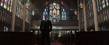 Movie still from “Captain America: Civil War” (2016), directed by Anthony Russo – A man in a suit standing in front of stained glass windows in a church; Wide shot, Low angle