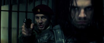 Movie still from “Captain America: Civil War” (2016), directed by Anthony Russo – A man wearing a red beret and holding a gun; Close Up shot, Over the shoulder angle