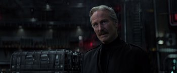 Movie still from “Captain America: Civil War” (2016), directed by Anthony Russo – An older man in a black shirt is looking at the camera; Close Up shot, Low angle