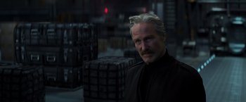 Movie still from “Captain America: Civil War” (2016), directed by Anthony Russo – A man with a beard and mustache in a warehouse; Close Up shot, Over the shoulder angle