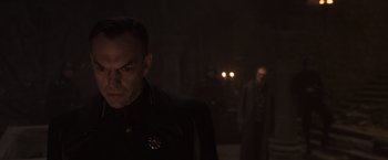 Movie still from “Captain America: The First Avenger” (2011), directed by Joe Johnston – A man standing next to another man in a dark room; Close Up shot, Over the shoulder angle