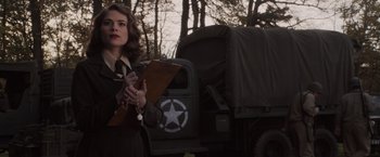 Movie still from “Captain America: The First Avenger” (2011), directed by Joe Johnston – A woman holding a clipboard standing next to a truck; Medium shot, Over the shoulder angle
