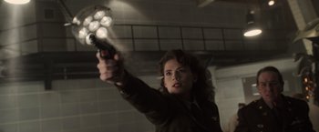 Movie still from “Captain America: The First Avenger” (2011), directed by Joe Johnston – A woman holding a gun in a room; Medium shot, Over the shoulder angle