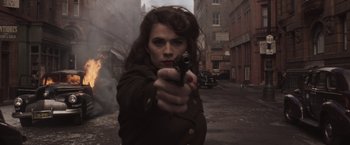Movie still from “Captain America: The First Avenger” (2011), directed by Joe Johnston – A woman is holding a gun in the middle of the street; Close Up shot, Low angle