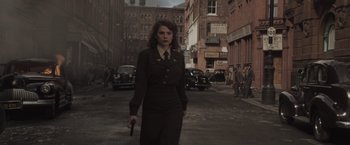Movie still from “Captain America: The First Avenger” (2011), directed by Joe Johnston – A woman is walking down the street holding a gun; Medium shot, Low angle