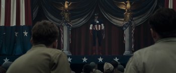 Movie still from “Captain America: The First Avenger” (2011), directed by Joe Johnston – A man dressed as captain america on a stage; Medium shot, Low angle