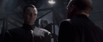 Movie still from “Captain America: The First Avenger” (2011), directed by Joe Johnston – A man wearing a suit and tie standing next to another man wearing glasses; Close Up shot, Over the shoulder angle