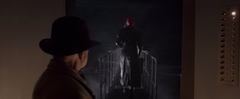Movie still from “Captain America: The First Avenger” (2011), directed by Joe Johnston – A man wearing a red hat and a black coat is standing on a bridge; Wide shot, Low angle