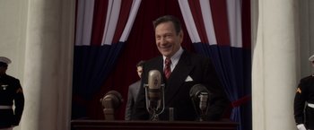 Movie still from “Captain America: The First Avenger” (2011), directed by Joe Johnston – A man wearing a suit and tie standing in front of microphones; Medium shot, Over the shoulder angle
