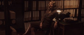 Movie still from “Captain America: The First Avenger” (2011), directed by Joe Johnston – A woman sitting on a chair in front of a bookshelf; Medium shot, Low angle