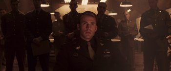 Movie still from “Captain America: The First Avenger” (2011), directed by Joe Johnston – A man in a military uniform is posing for a picture; Medium shot, Low angle