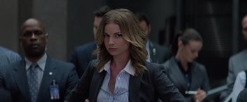 Movie still from “Captain America: The Winter Soldier” (2014), directed by Anthony Russo – A woman in a business suit is standing in front of a group of people; Close Up shot, Over the shoulder angle