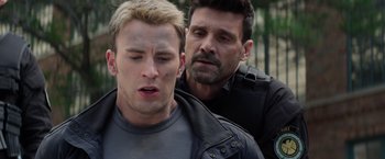 Movie still from “Captain America: The Winter Soldier” (2014), directed by Anthony Russo – A man standing next to another man in a leather jacket; Close Up shot, Over the shoulder angle