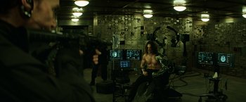 Movie still from “Captain America: The Winter Soldier” (2014), directed by Anthony Russo – A man sitting on a chair in front of a camera; Medium shot, Over the shoulder angle