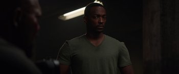 Movie still from “Captain America: The Winter Soldier” (2014), directed by Anthony Russo – A man in a green t - shirt is in a dark room; Medium shot, Low angle
