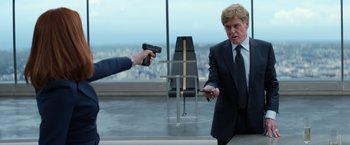 Movie still from “Captain America: The Winter Soldier” (2014), directed by Anthony Russo – A man in a suit and tie holding a cell phone; Medium shot, Over the shoulder angle