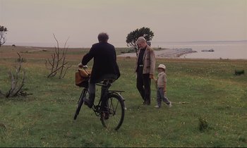 Movie still from “The Sacrifice” (1986), directed by Andrei Tarkovsky – Two men and a child are standing in a field; Wide shot, High angle